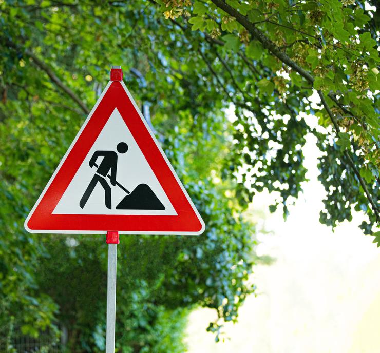 Baustellenschild vor grünem Baum